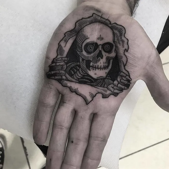 Skeleton design on a palm tattoo, showcasing intricate black ink details.