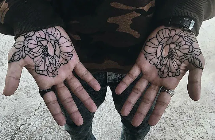 Intricate flower palm tattoos on both hands, showcasing artistic design.