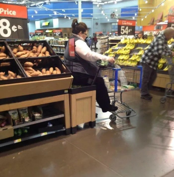 Señora sentándose sobre las manzanas en el supermercado