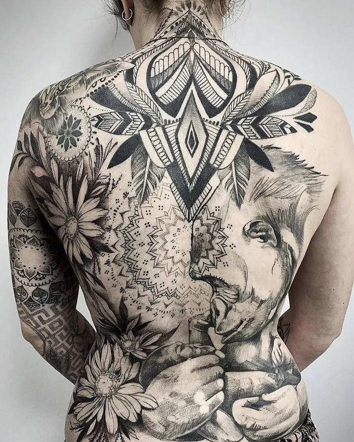 Intricate back tattoo featuring geometric patterns, flowers, and animal motifs.