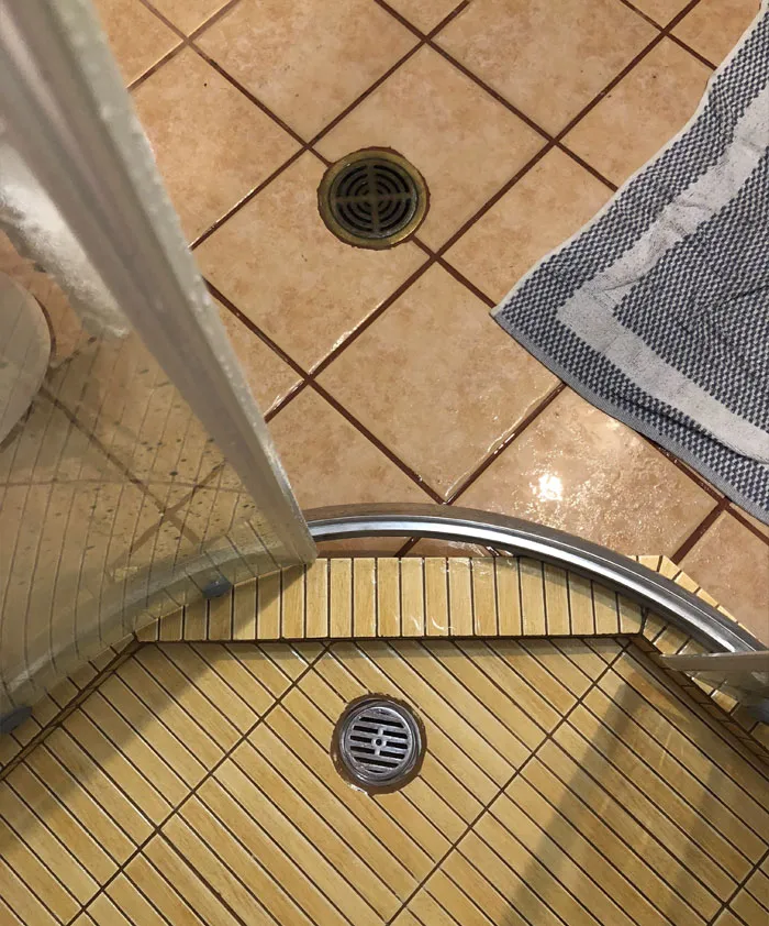 Esta mampara curva y una base de ducha cuadrada hacen que el suelo se llene de agua