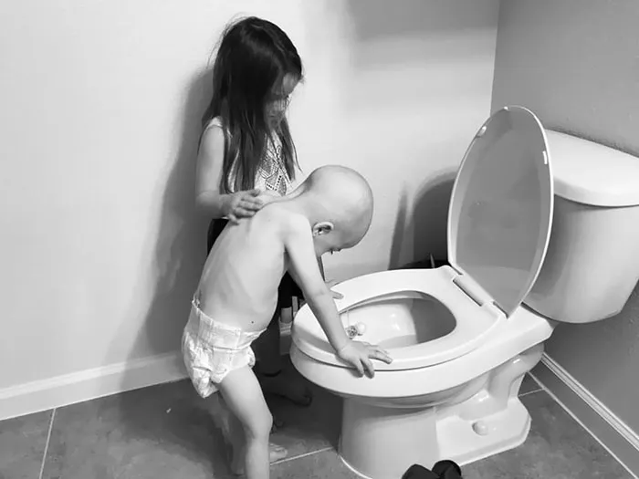5-Year-Old Girl Gently Supporting Her 4-Year-Old Brother As The Side Effects Of Chemotherapy Disrupt Their Playtime