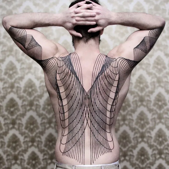Intricate geometric back tattoo, showcasing impressive art on a man's back with arms raised against a patterned background.