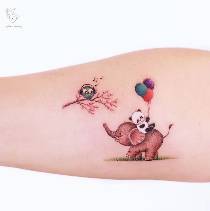 Tattoo design of a panda on an elephant with balloons, next to a singing bird on a branch, on human skin.