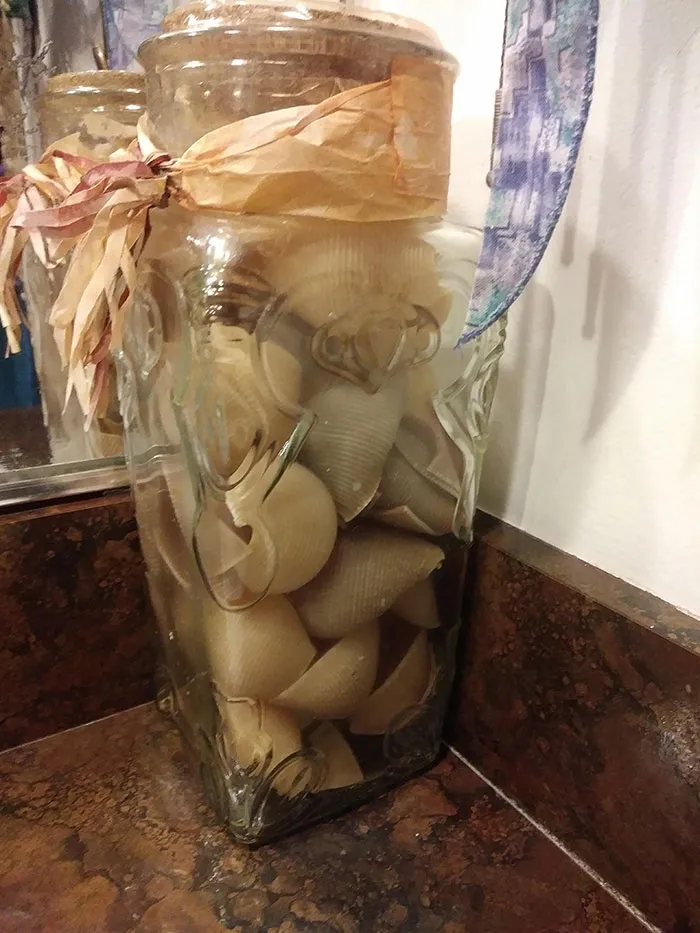 Estaba limpiando el baño de mi mamá y me di cuenta de que este frasco, que ha estado allí por 15 años, no está lleno de conchas de mar. Está lleno de conchas de pasta