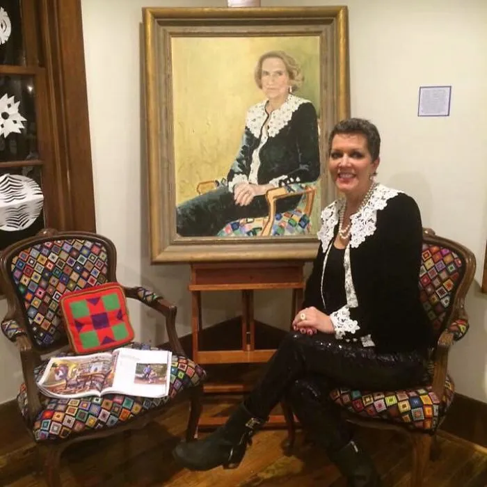Retrato de mi abuela sentada en una silla que bordó. Yo estoy sentada en la silla que ella me ayudó a bordar, con su mismo traje. Lo heredé todo