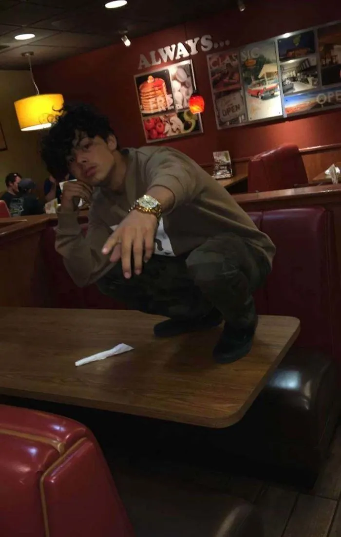 De cuclillas sobre la mesa de un restaurante para tomarse una fotografía