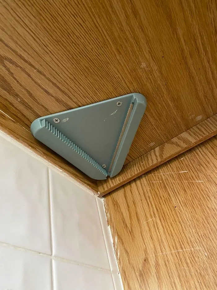 On The Underside Of Our Cabinet In The House We Recently Bought, Built In The 70s. Plastic With Metal Teeth On One Side, Very Dull. Each Side Is ~4 Inches Long. What Is This Thing?