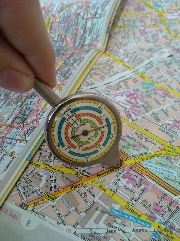 Hand holding a map measuring tool over a colorful city map, revealing the unseen details of navigation.