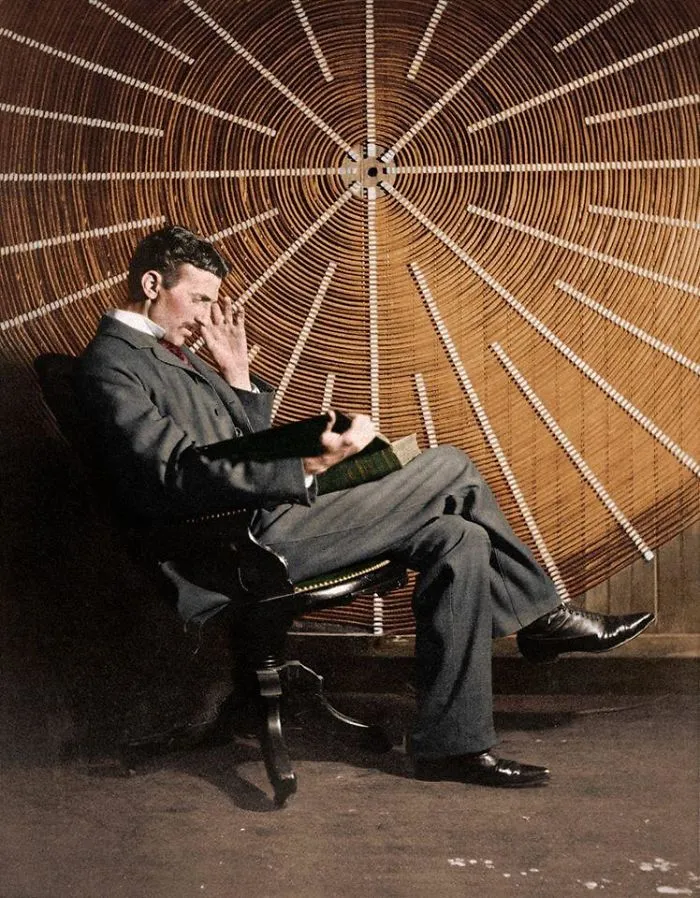 Nikola Tesla, leyendo  'Theoria Philosophiae Naturalis', frente a la bobina espiral de su transformador de alta frecuencia, en Nueva York