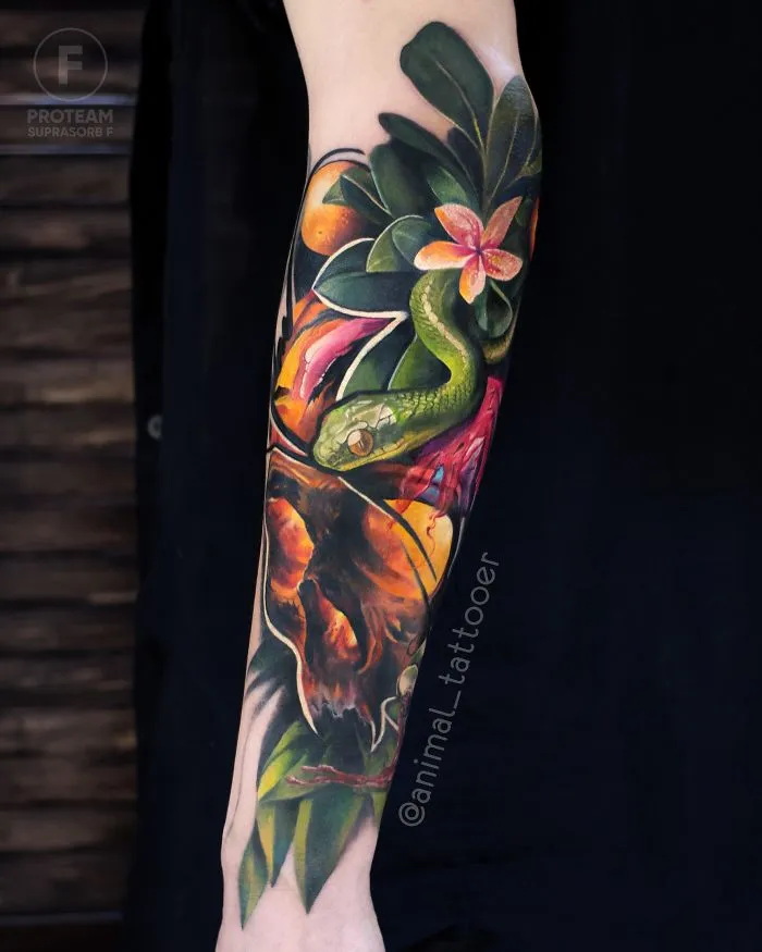 Colorful and bright animal tattoo featuring a green snake and tropical flowers on a forearm.
