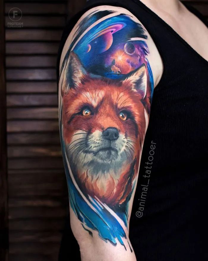 Colorful and bright fox tattoo with a cosmic background on a person's upper arm.