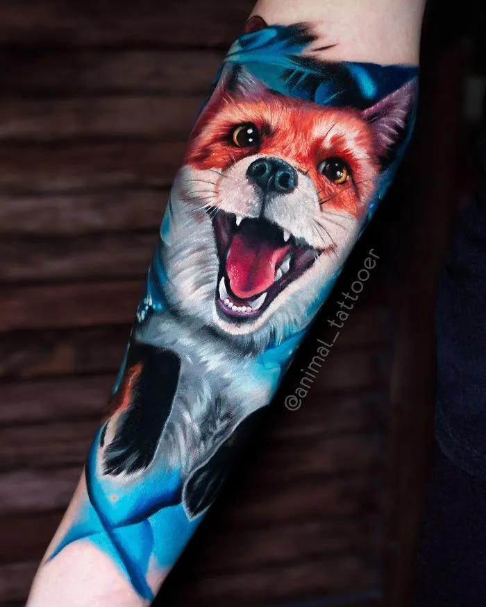 Colorful and bright animal tattoo of a vibrant fox on a forearm.