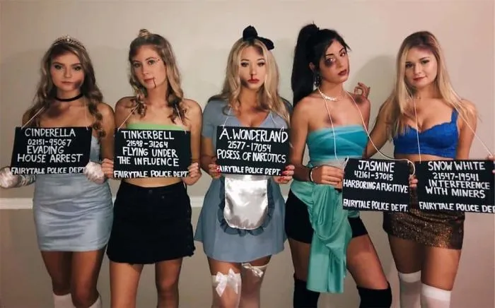 Group of friends dressed as arrested Disney princesses, showing off unique Halloween costumes.