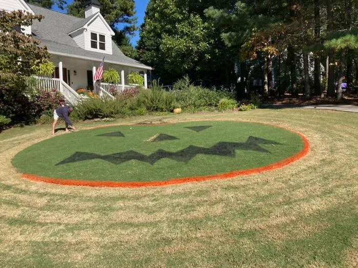 Large jack-o-lantern face painted on lawn as a funny and frightening Halloween decoration in front of a house