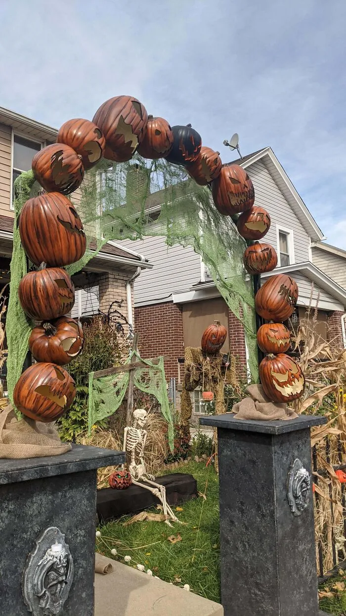 Halloween decorations featuring a pumpkin arch, skeleton, and spooky figures creating a funny and frightening outdoor display.