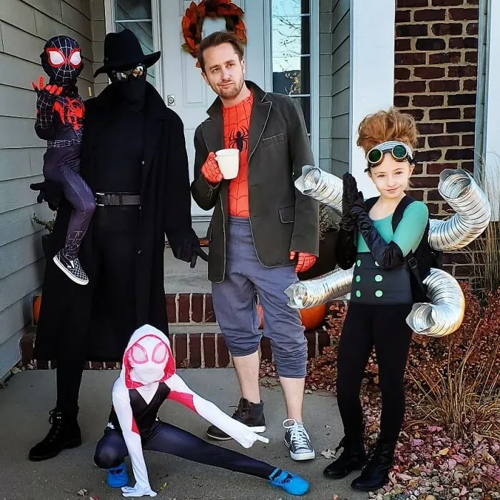 A family dressed up in Spider-Man themed Halloween costumes posing on their porch