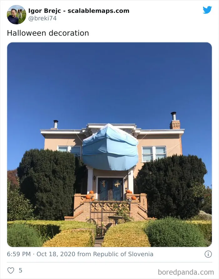 House decorated for Halloween with a giant blue face mask covering the entrance, surrounded by pumpkins and greenery.