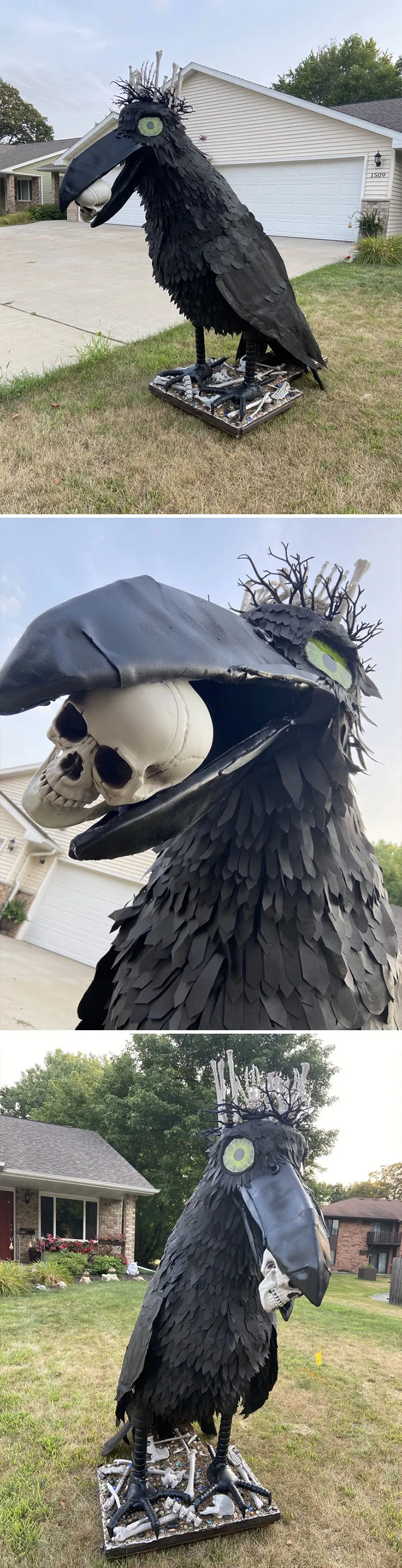 Large black Halloween decoration of a raven holding a skull, standing on a base with skeleton bones outdoors in a yard.