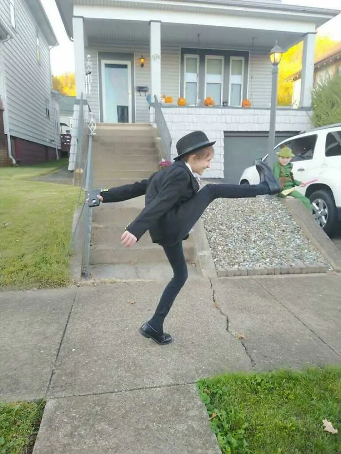 A young boy posing in a funny Ministry of Silly Walks Halloween costume on a sidewalk.