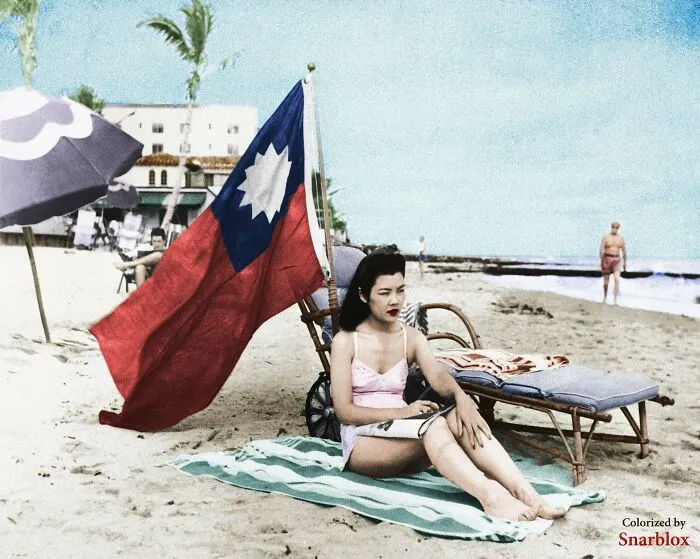 Ruth Lee, dueña de un restaurante chino, con una bandera china para que no la confundan con una japonesa, mientras toma el sol en Miami. Diciembre de 1941
