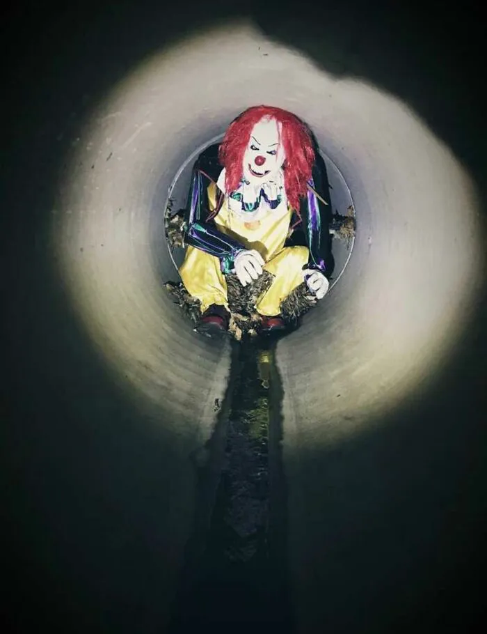 Maniquí payaso atado a una reja en una tubería de desagüe, a 0,8 kms de la entrada
