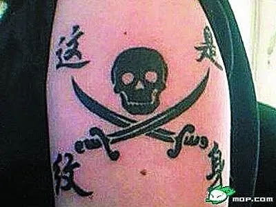 Tattoo with a skull and crossed swords, featuring foreign language text on a person's arm.