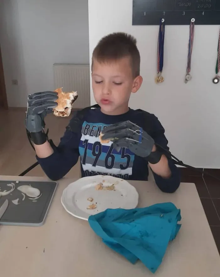 Mi amigo comiéndose una hamburguesa con las manos prostéticas que le he diseñado y construido