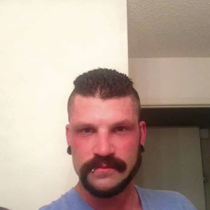 Man showing off his monkey tail beard style in a casual setting.