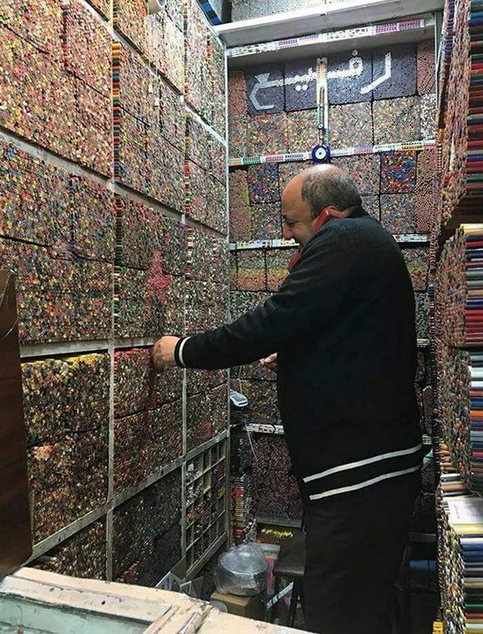 Man organizing a colorful collection of pencils in a small shop, showcasing the unseen side of creativity.