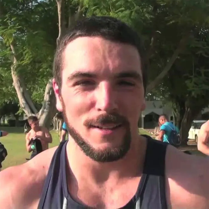 Man outdoors with a monkey tail beard, wearing a sleeveless top.