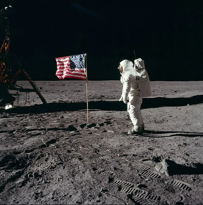 Astronaut standing next to American flag on the moon surface illustrating interesting facts people didn’t learn at school.