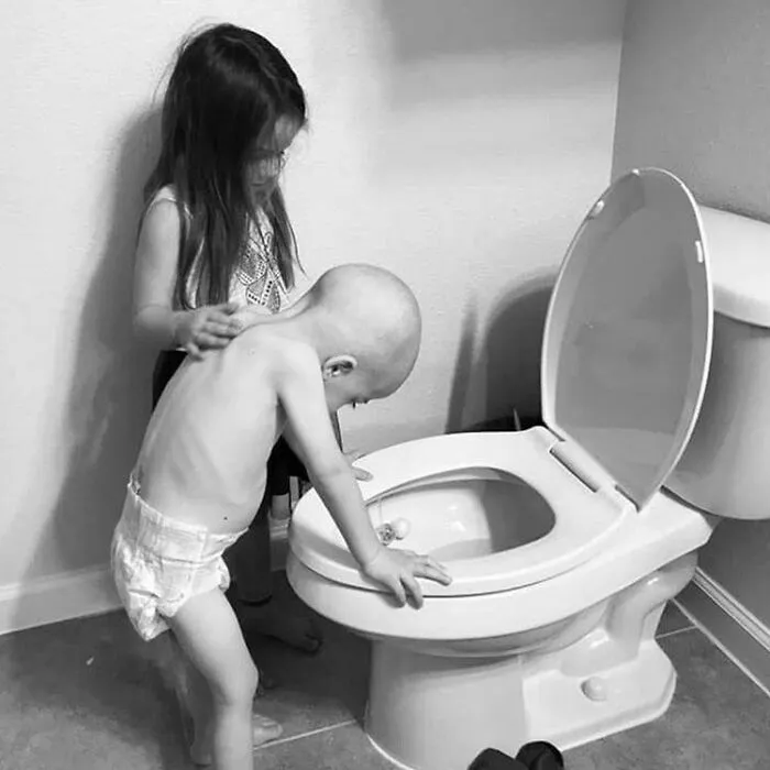 Una niña de 5 años apoyando amablemente a su hermano de 4 años mientras los efectos secundarios de la quimioterapia interrumpen su tiempo de juego
