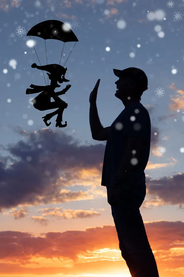 Silhouette of a person high-fiving a parachuting character cutout at sunset, evoking Valentine's Day vibes.