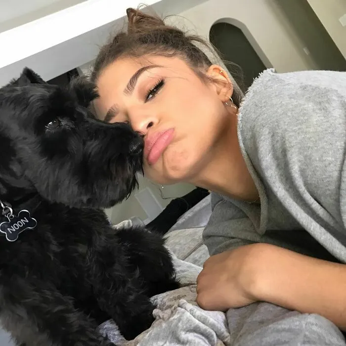 Celebrity cuddling a black dog named Noon, showing immense love and affection for dogs in a cozy indoor setting.