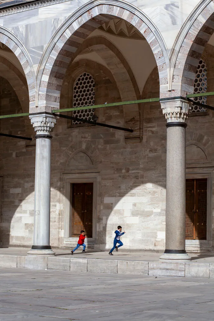The Pillars Of The Suleymaniye Mosque And The Shadows Of The Arches Create Spectacular Frames Around The Kids Running And Playing Joyfully