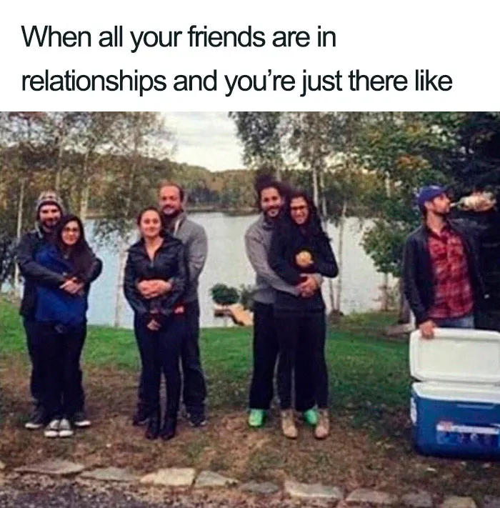 A single person stands next to couples by a lake, humorously illustrating single life.