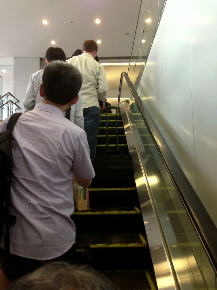 People standing in a line on an escalator, showcasing unique social etiquette in Japan.