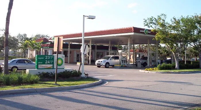 Gas station with cars refueling, surrounded by trees and clear sky, illustrating daily life and common scenes.
