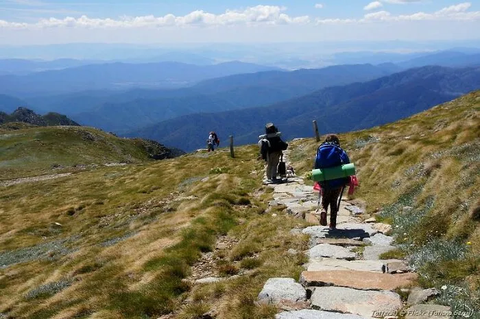 Hikers walking on a mountain trail under blue sky, illustrating the concept of weird laws from around the world.
