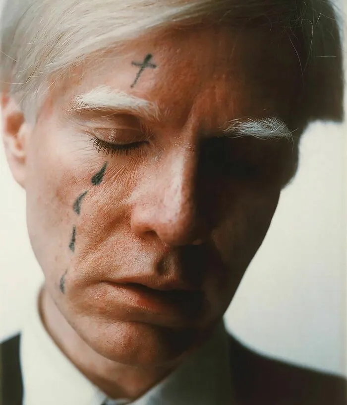 Person with artistic face tattoos, eyes closed, showcasing creativity and transformation.
