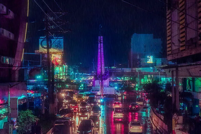 Monumento Circle During A Rainy Monsoon Night. A Historical Monument Surrounded By Motels, Billboards, Shopping Malls, And A Nightlife District