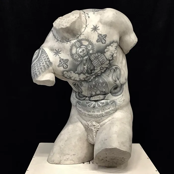 Tattooed sculpture by Italian artist showcases intricate designs on a classic marble torso.