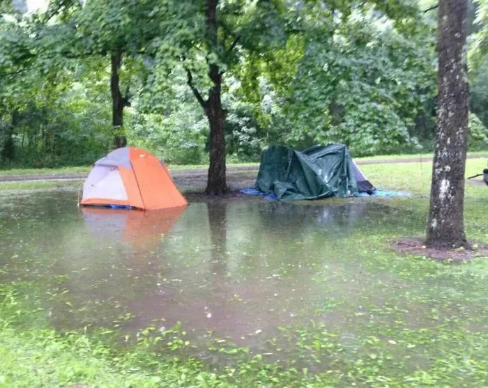 Flooded campsite with tents surrounded by water and trees, showcasing nature moments that make people go well that sucks.