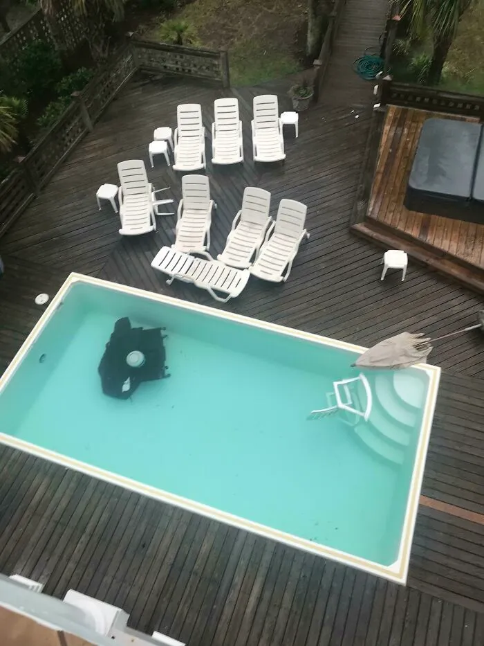 Pool filled with outdoor furniture submerged in water on a wooden deck, showing a nature mishap that makes people go well that sucks.