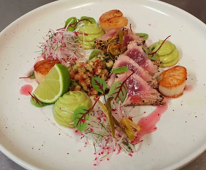 Atún de aleta amarilla, vieiras selladas, puré de palta y wasabi, salsa de pepinillos, ensalada de rabanitos, y vinagre de hibisco