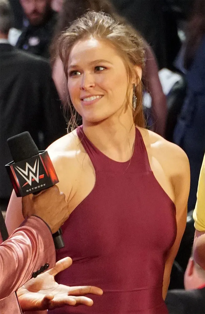 A woman in a maroon dress smiling while being interviewed at an event, highlighting really cool and interesting facts.