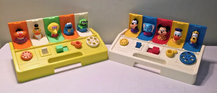 Vintage toy sets from the '70s and '80s featuring pop-up characters on yellow and white bases.