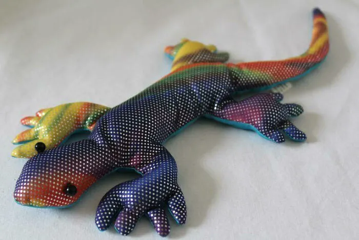 Vintage toy lizard with a vibrant rainbow pattern from the '70s, '80s, or '90s, evoking childhood nostalgia.