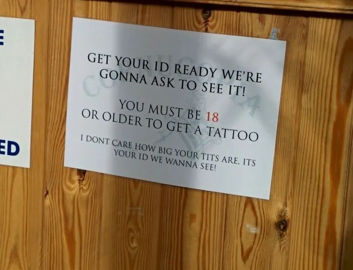 Funny sign about age verification for tattoos, emphasizing the importance of showing ID regardless of appearance.